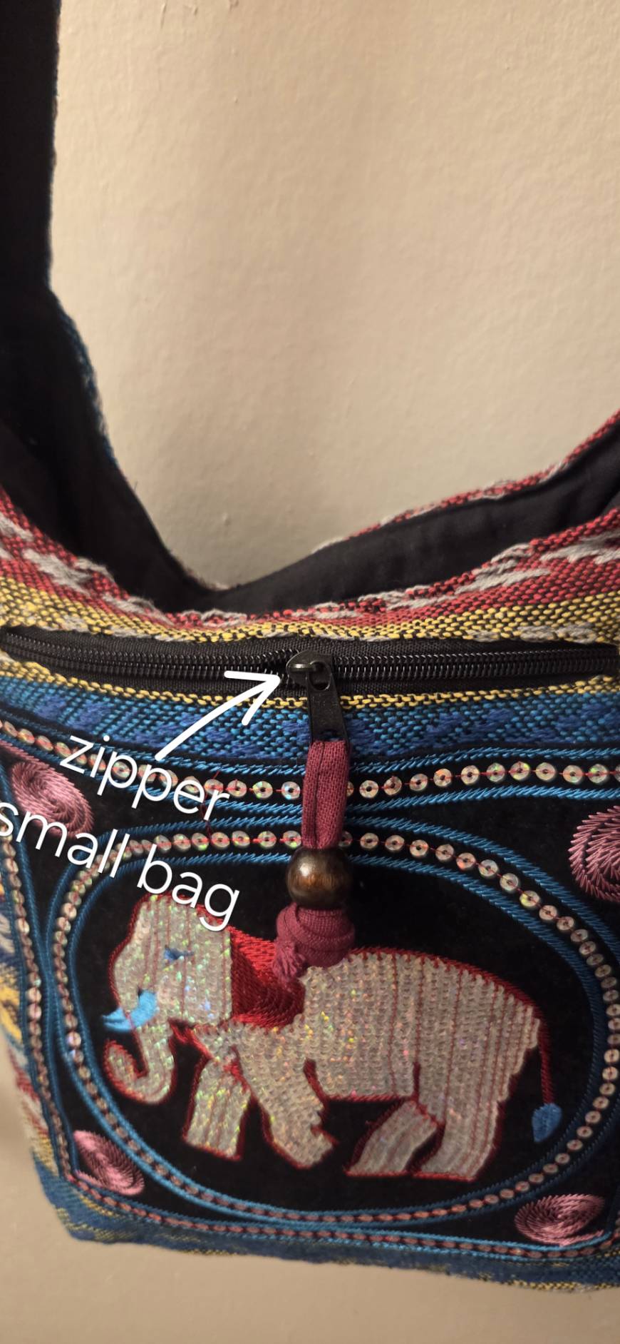 Exterior zippered small bag pocket detail with decorative bead zipper pull