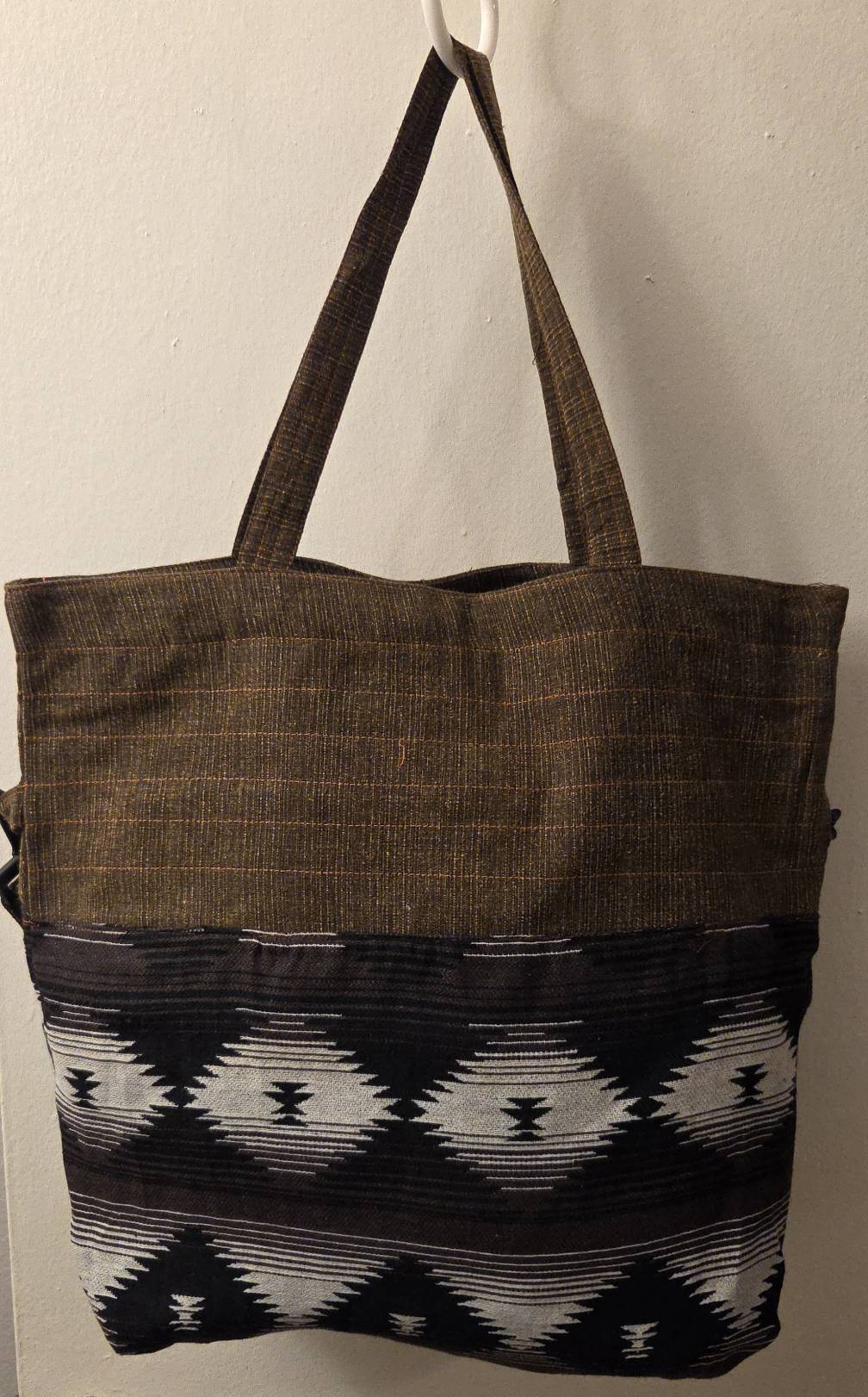 Thai cotton boho tote bag ET-07 – dark brown body with bold brown white geometric aztec woven panel, detachable strap, lifestyle hanging shot with potted plant