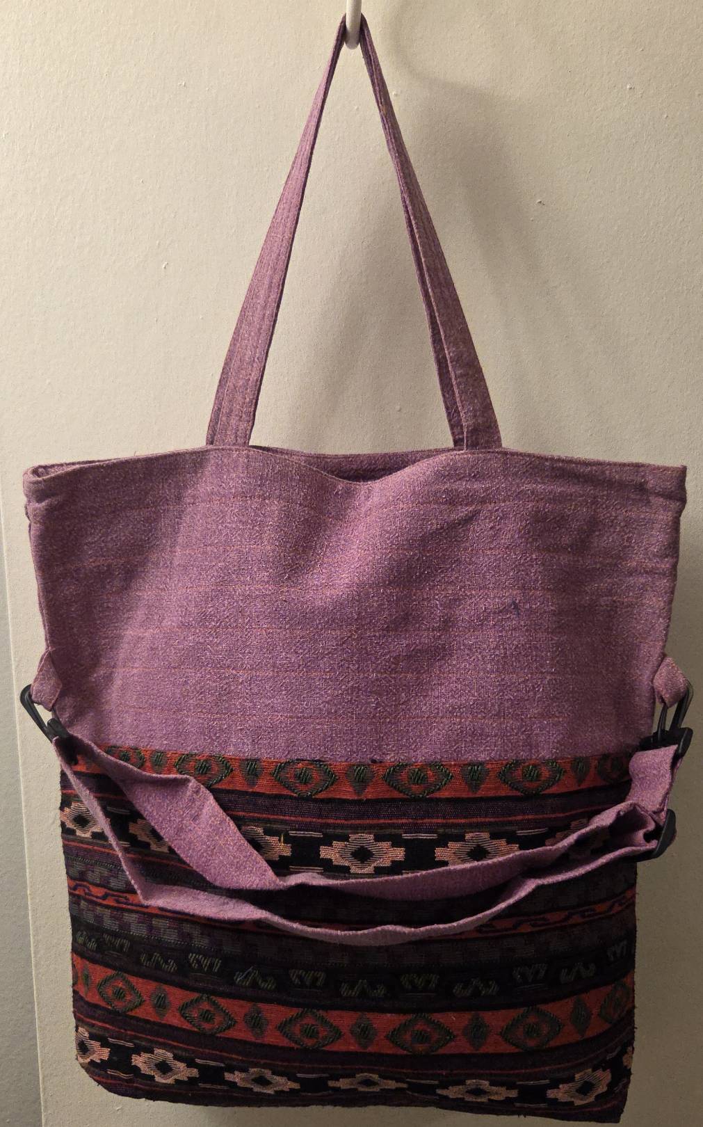 Thai cotton boho tote bag ET-09 – lavender mauve body with bold multicolor aztec geometric woven panel, detachable crossbody strap attached, lifestyle hanging shot on white wall