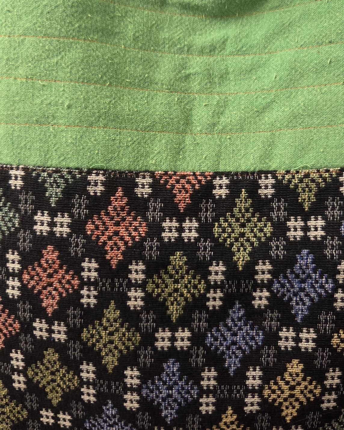 Thai cotton boho tote bag ET-10 – green body with dark multicolor horizontal tribal woven panel, lifestyle hanging shot on white wall